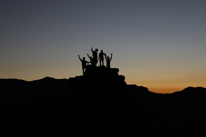 Persönlichkeitsentwicklung - Team erreicht gemeinsam den Gipfel bei einer Wanderung.